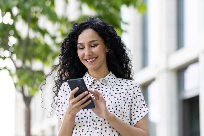 Smiling woman using smartphone outdoors - Microfridge Rental Order